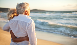 older man and woman hugging on the beach